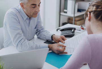 A male advisor assists a woman in filling out a form.