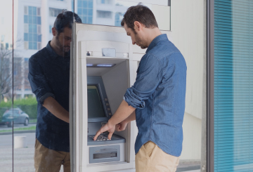 A man uses an outdoor ATM on a sunny day.